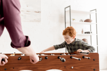 A child and an adult playing foosball