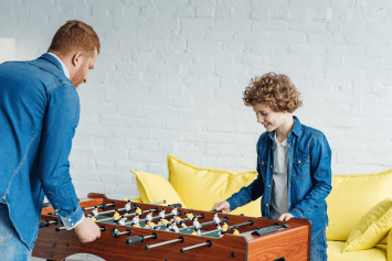 A child and father playing foosball together