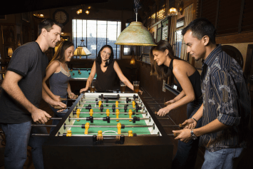 A group of friends playing foosball in a pub