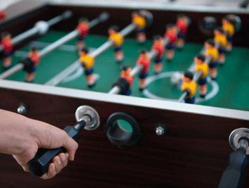 Close up of a hand gripping a foosball table handle