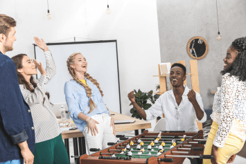 Men and women playing foosball in an office