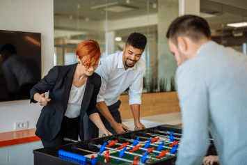 Men and a woman playing foosball in the office